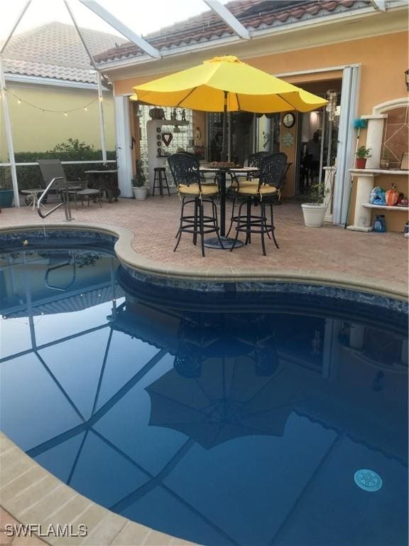 view of pool with glass enclosure and a patio area