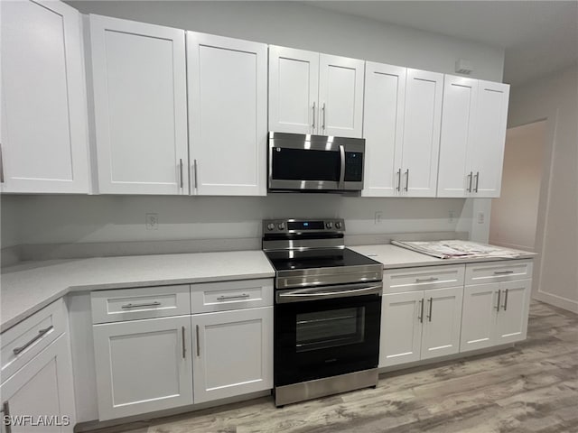 kitchen with stainless steel appliances, white cabinetry, and light wood-type flooring