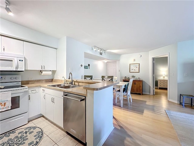 kitchen featuring white cabinetry, white appliances, kitchen peninsula, and sink