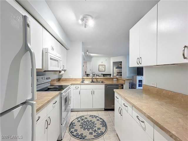 kitchen with white cabinetry, sink, white appliances, and light tile patterned floors