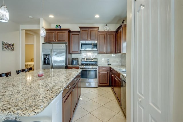 kitchen with tasteful backsplash, appliances with stainless steel finishes, hanging light fixtures, and a breakfast bar area