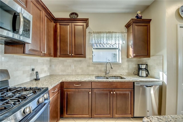 kitchen featuring light stone counters, sink, tasteful backsplash, and appliances with stainless steel finishes