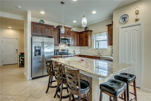 kitchen featuring appliances with stainless steel finishes, a breakfast bar, sink, hanging light fixtures, and a center island