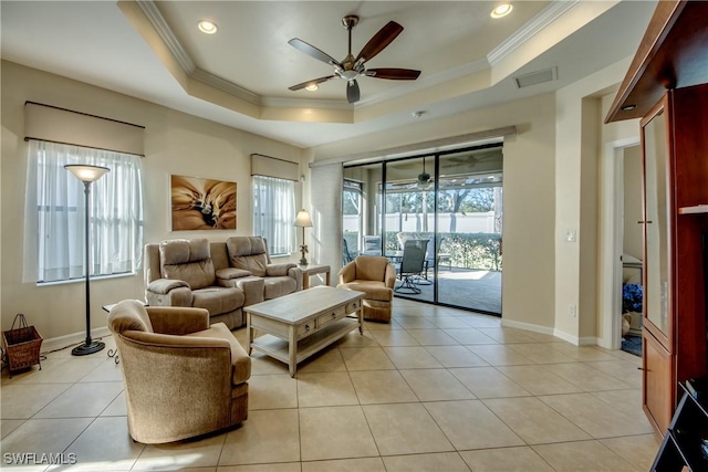 tiled living room featuring a raised ceiling, crown molding, and plenty of natural light