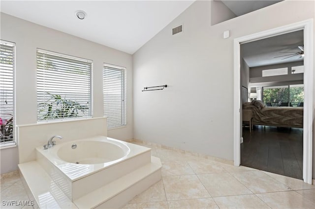 bathroom with ceiling fan, lofted ceiling, a bathing tub, and tile patterned flooring