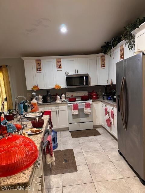 kitchen with sink, light tile patterned floors, stainless steel appliances, and white cabinets