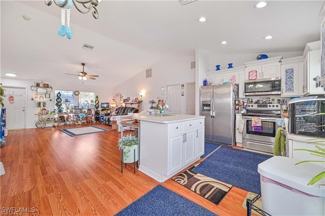 kitchen featuring vaulted ceiling, stainless steel appliances, white cabinets, and a kitchen island