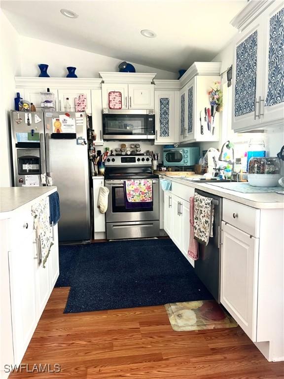 kitchen with white cabinetry, lofted ceiling, stainless steel appliances, and dark hardwood / wood-style floors