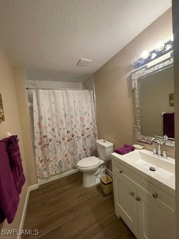 bathroom featuring vanity, a textured ceiling, wood-type flooring, and toilet