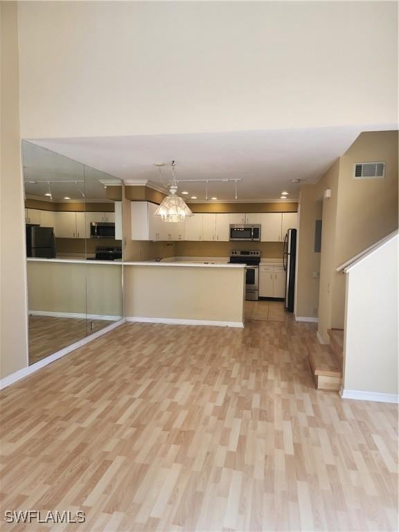 kitchen featuring rail lighting, white cabinetry, appliances with stainless steel finishes, and light hardwood / wood-style flooring