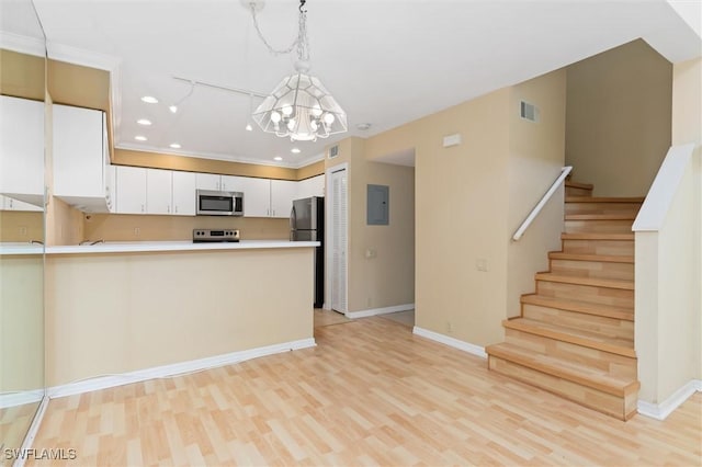 kitchen featuring white cabinets, appliances with stainless steel finishes, a peninsula, light countertops, and pendant lighting