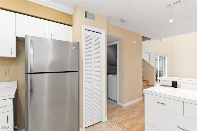 kitchen with washer / clothes dryer, light countertops, visible vents, freestanding refrigerator, and white cabinetry