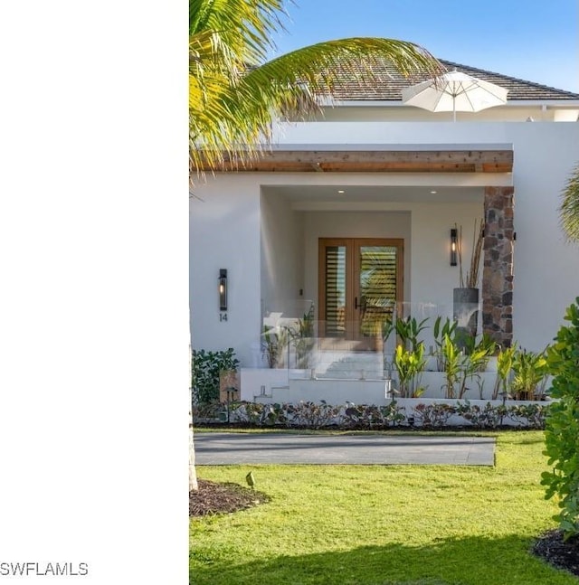 doorway to property with a lawn and french doors