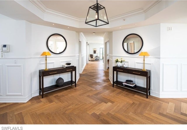 corridor featuring ornamental molding, dark parquet floors, and a tray ceiling