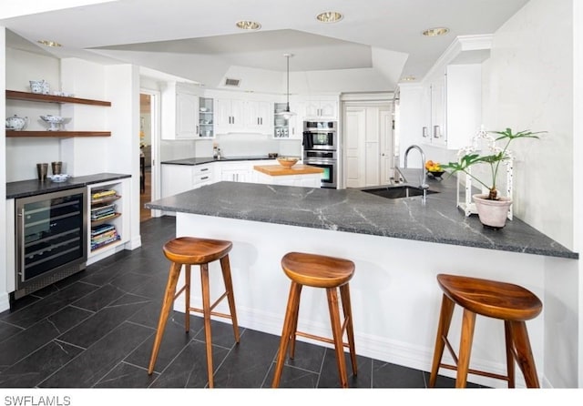 kitchen featuring white cabinetry, sink, beverage cooler, and kitchen peninsula