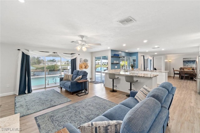 living room with visible vents, a ceiling fan, recessed lighting, light wood finished floors, and baseboards