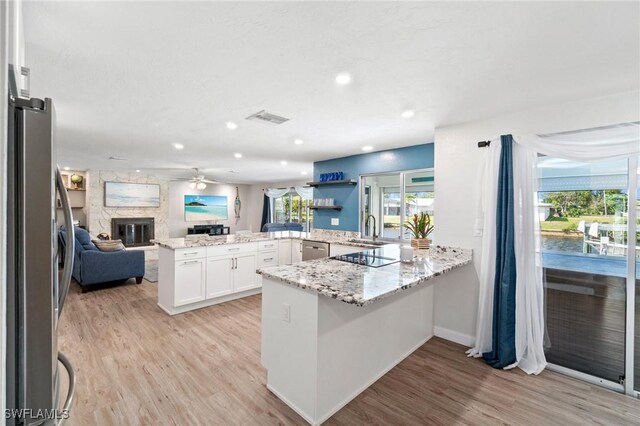 kitchen featuring a ceiling fan, a sink, open floor plan, stainless steel appliances, and a peninsula