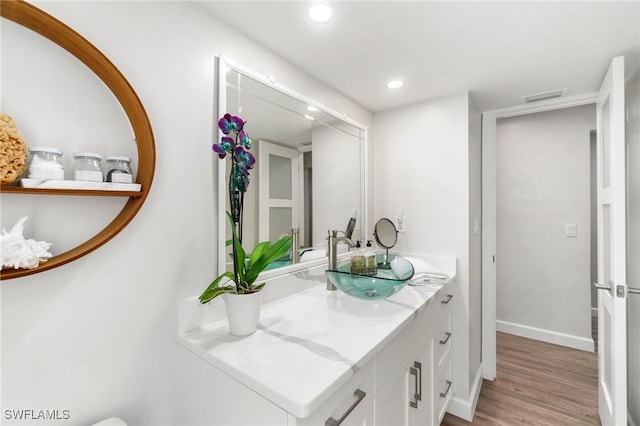 bathroom with visible vents, baseboards, recessed lighting, wood finished floors, and vanity
