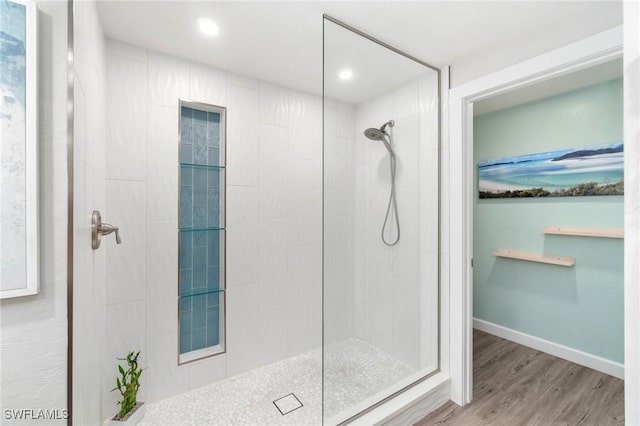 bathroom with recessed lighting, wood finished floors, baseboards, and a tile shower