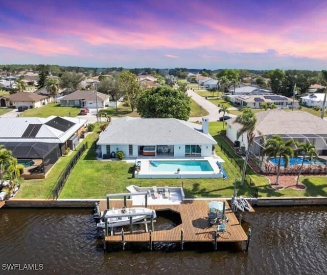 aerial view at dusk with a residential view and a water view