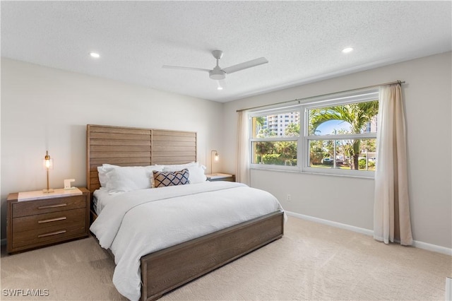 bedroom featuring ceiling fan, light colored carpet, and a textured ceiling