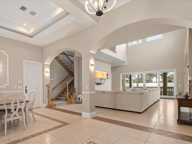 living room featuring light tile patterned floors, a raised ceiling, a chandelier, and a high ceiling