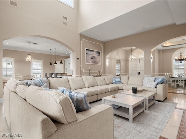 living room featuring a high ceiling, a chandelier, a healthy amount of sunlight, and light tile patterned flooring