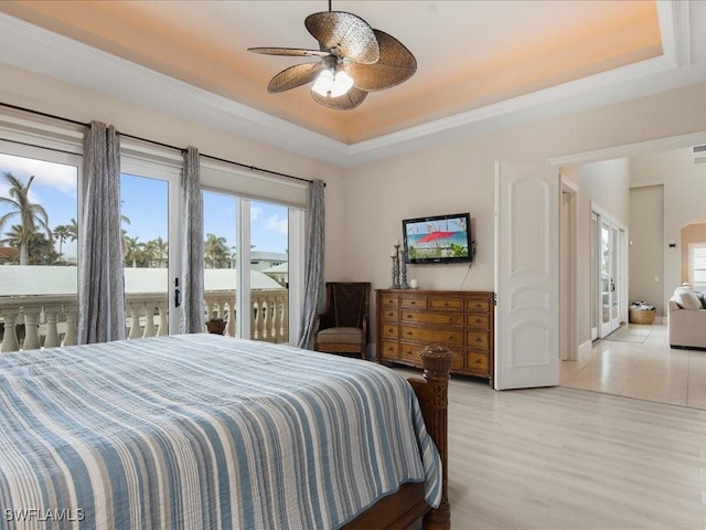 bedroom with a raised ceiling, access to exterior, ceiling fan, and light hardwood / wood-style flooring