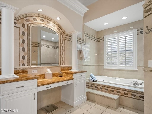 bathroom featuring vanity, a relaxing tiled tub, tile patterned floors, and ornate columns