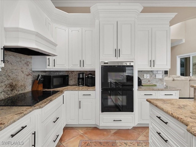 kitchen with light tile patterned flooring, custom range hood, white cabinets, and black appliances