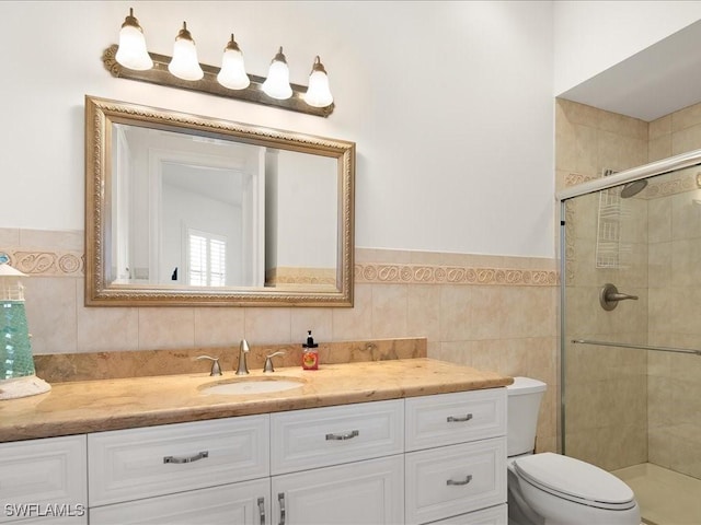 bathroom featuring vanity, toilet, tile walls, and a shower with shower door