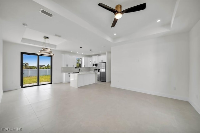 unfurnished living room featuring ceiling fan and a tray ceiling