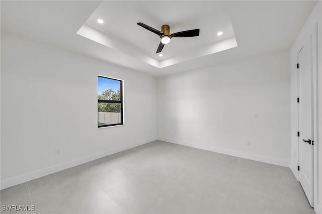 spare room with ceiling fan and a raised ceiling