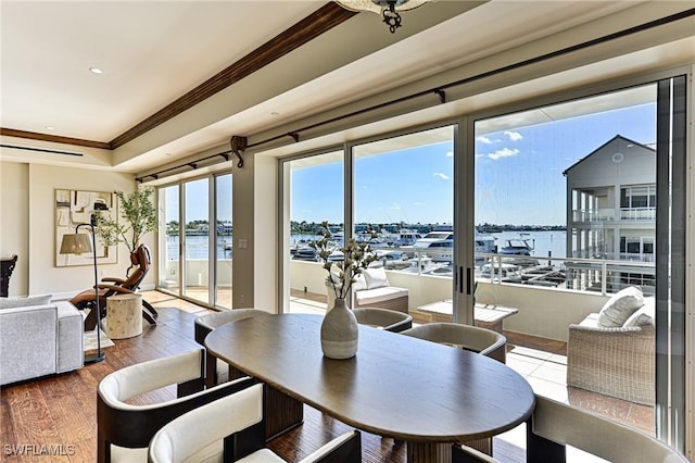 dining room with crown molding, hardwood / wood-style flooring, and a water view