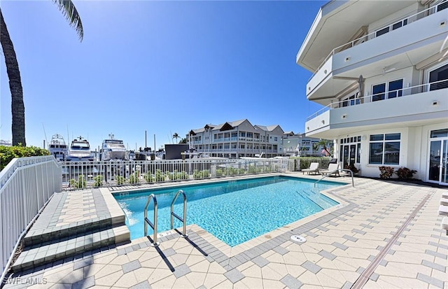 view of swimming pool featuring a patio and a water view