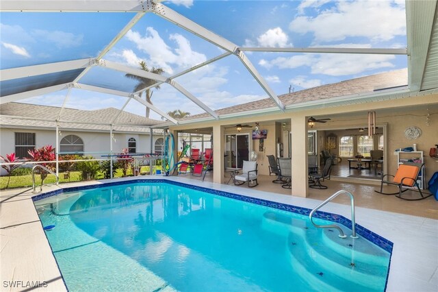 view of pool with a patio area, ceiling fan, and glass enclosure