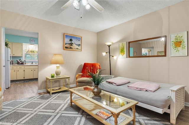 living room featuring ceiling fan, dark wood-type flooring, sink, and a textured ceiling