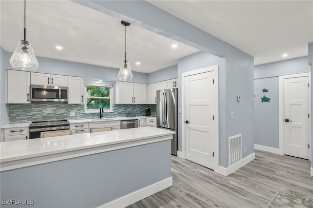 kitchen featuring sink, white cabinetry, tasteful backsplash, pendant lighting, and stainless steel appliances