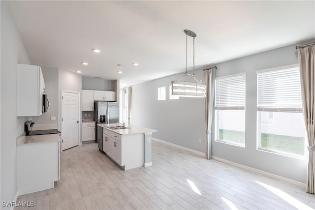 kitchen with sink, plenty of natural light, stainless steel appliances, a center island with sink, and decorative light fixtures