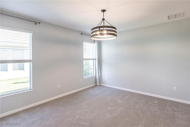 carpeted empty room with a chandelier