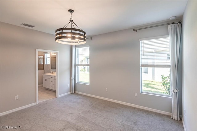 carpeted empty room featuring an inviting chandelier