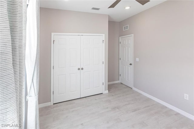 unfurnished bedroom with ceiling fan, light wood-type flooring, and a closet