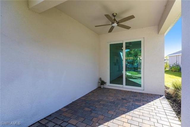 view of exterior entry with ceiling fan and a patio area