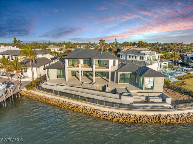 back house at dusk with a water view, an outdoor hangout area, and a patio