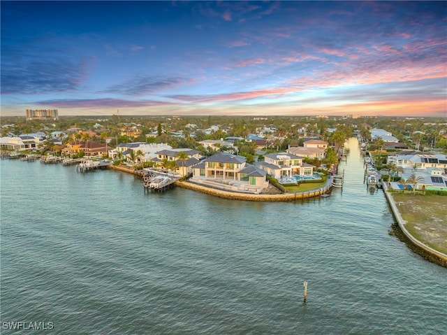 aerial view at dusk featuring a water view