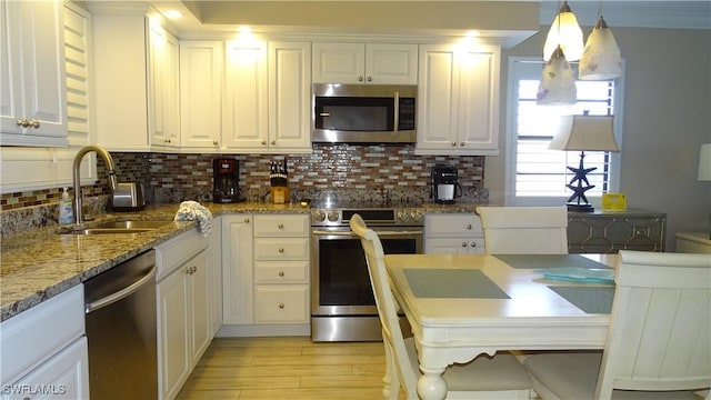 kitchen featuring stainless steel appliances, decorative light fixtures, sink, and white cabinets