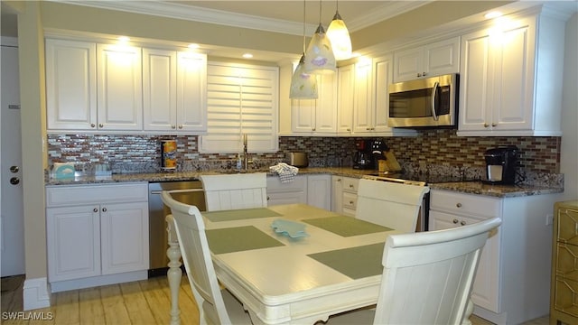 kitchen with pendant lighting, white cabinetry, stainless steel appliances, tasteful backsplash, and ornamental molding