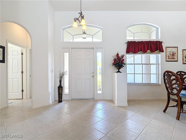 tiled entryway featuring a chandelier and a high ceiling