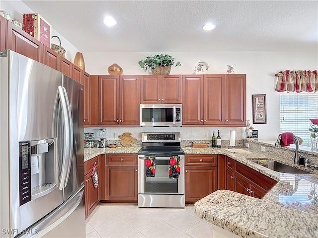 kitchen featuring light stone countertops, appliances with stainless steel finishes, sink, and kitchen peninsula