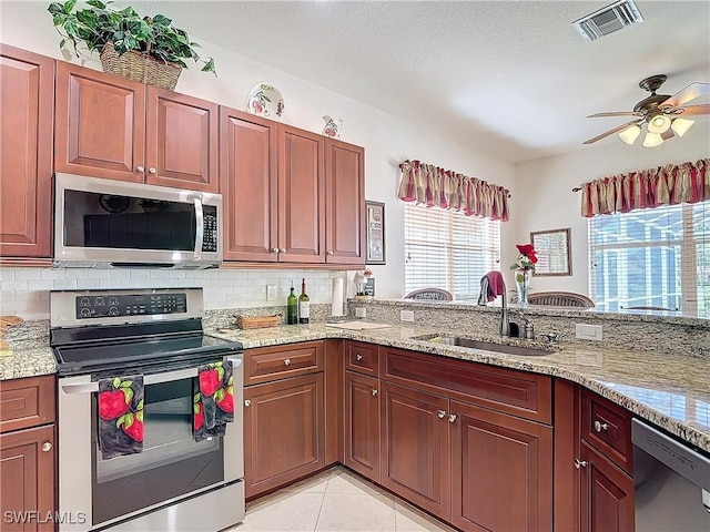 kitchen with tasteful backsplash, light stone countertops, appliances with stainless steel finishes, and sink